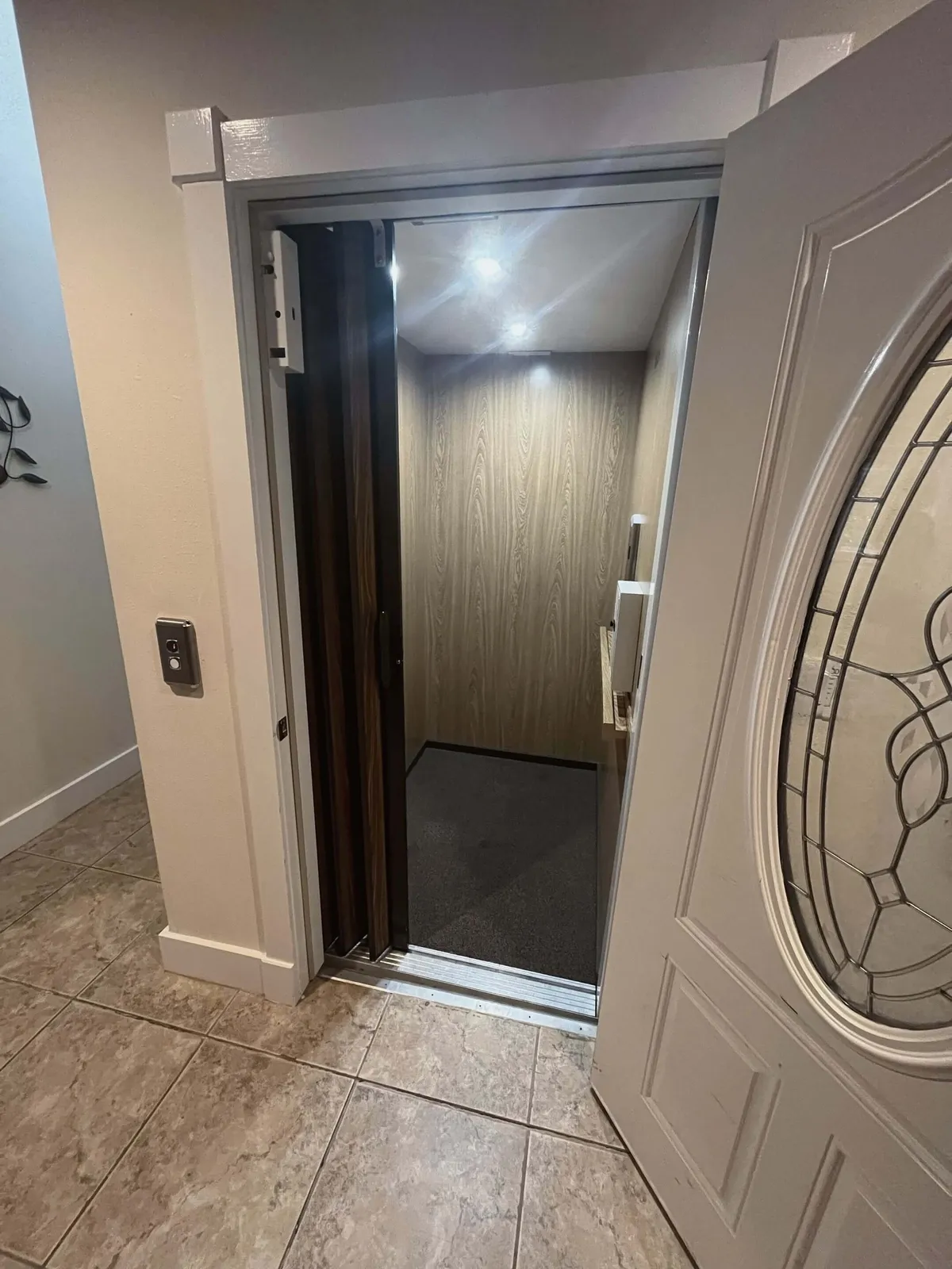 An interior view of a modern elevator entrance with a decorative door and tile flooring, emphasizing accessibility and ease of movement between floors for all generations.